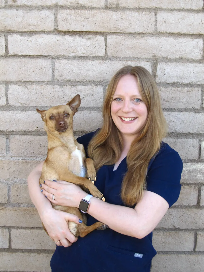 Catharine, RVT Supervisor, holding a small tan dog